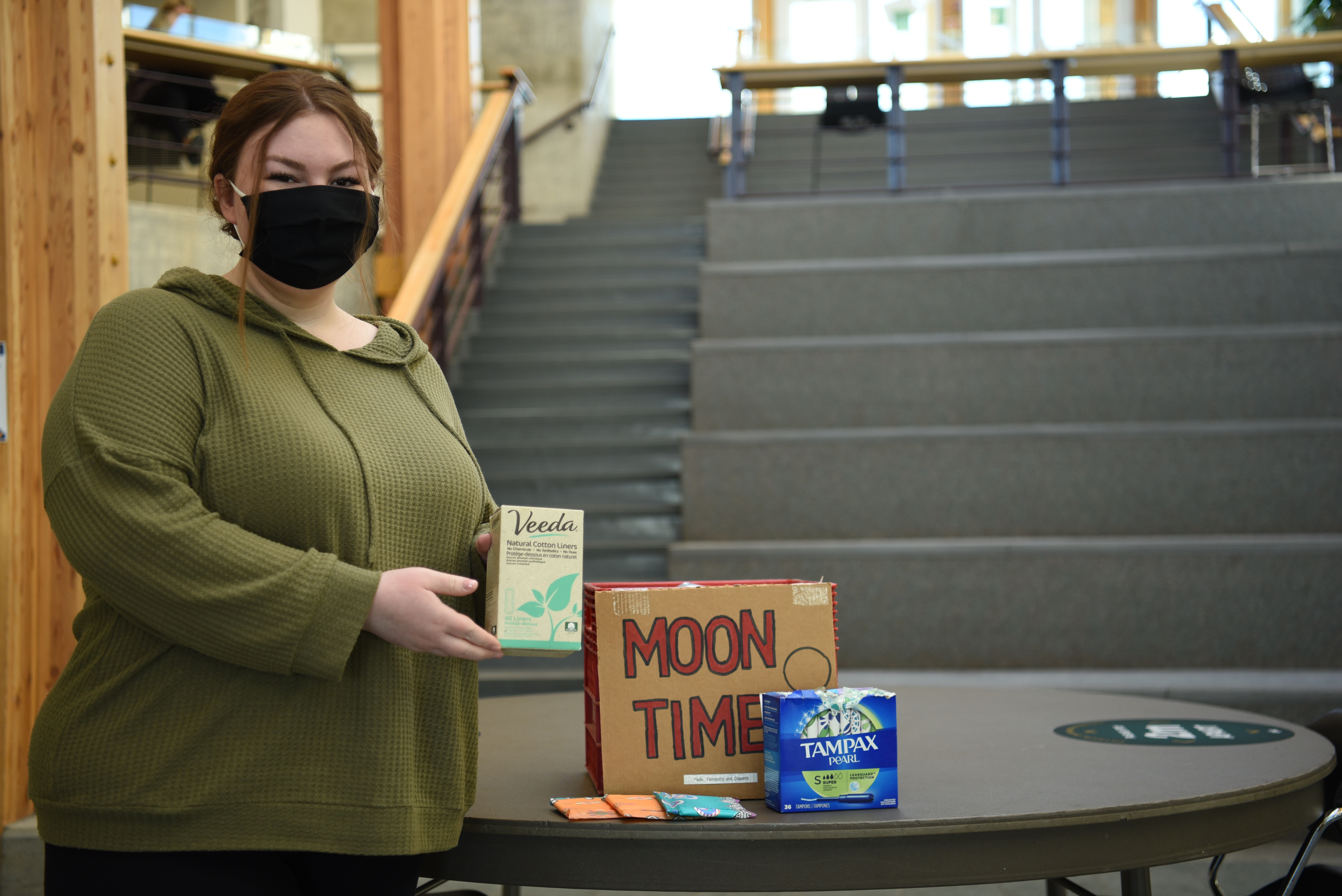 UNBC student Emily Erickson with menstrual products in the Canfor Winter Garden