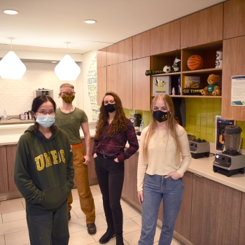 Four students stand in the kitchen in the Agora Dining Hall 