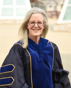Woman in royal blue and black academic regalia stands outside