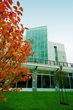 Exterior photo of a UNBC building with a nice red leafed tree in front