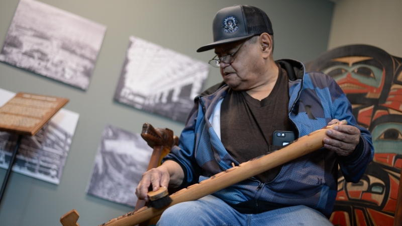 Ron Sebastian polishes the talking stick while sitting on one of the ceremonial chairs at UNBC 