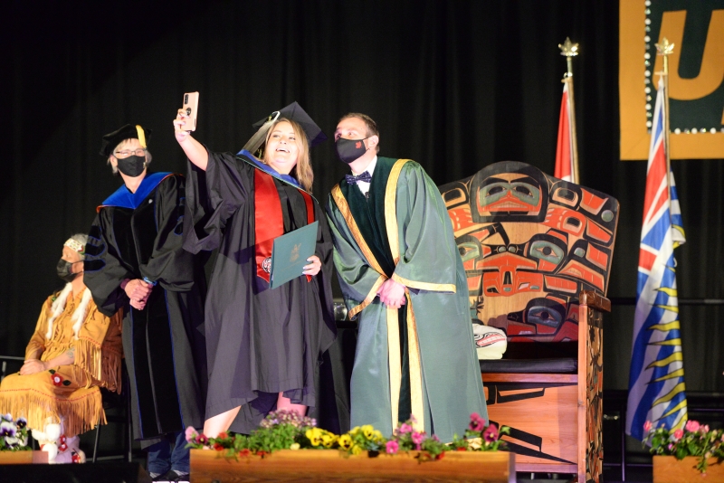 A graduate takes a selfie with the president at Convocation 