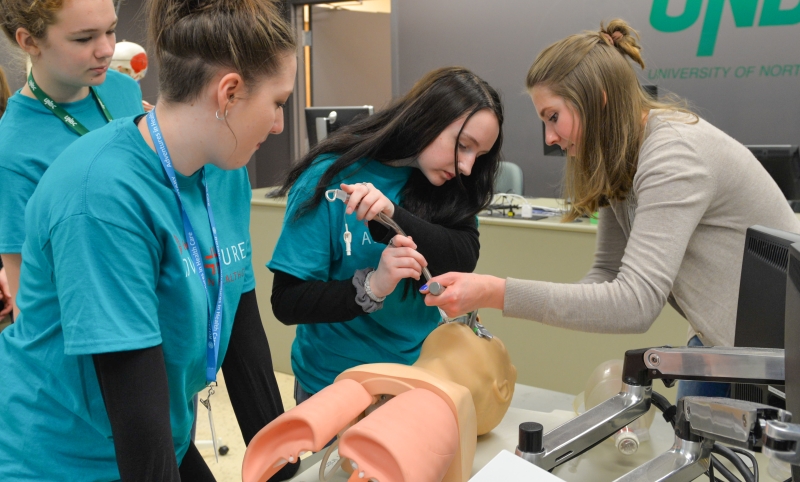 Three students practice intubation skills in a lab led by a medical student.