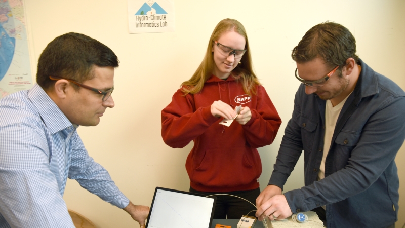 Assistant Professor Siraj ul Islam on his computer with research assistants Kaylee Barnes and Joel Caryk in lab