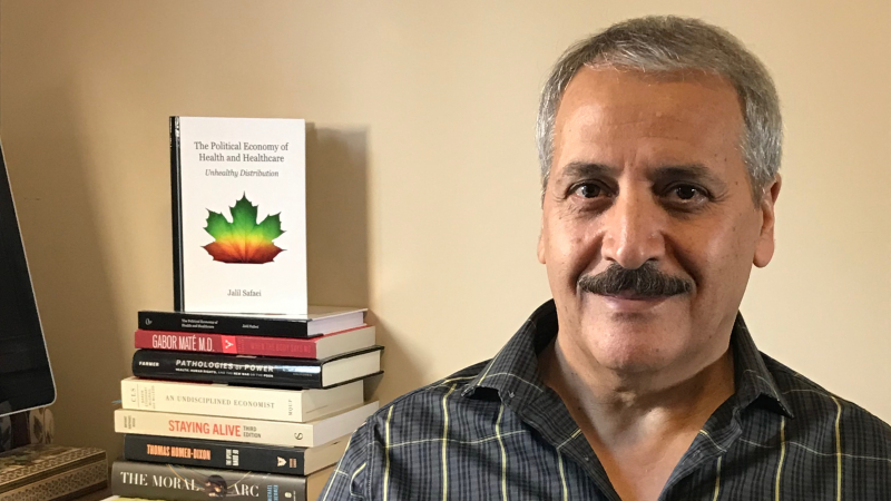 Economics Professor Dr. Jalil Safaei with his new book in the background