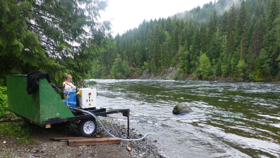 A person operates monitoring equipment on the Quesnel River 