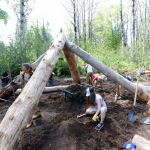 The basic frame is raised and students clear roots to start digging the pit.