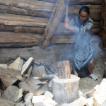 Jennifer Pighin, a teaching assistant, splits wood inside the completed pit house.