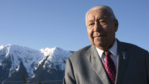 Joseph Gosnell Sr standing in the Nass Valley with mountains in the background.