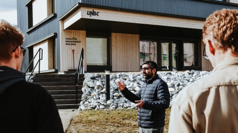 A person giving a tour in front of the Facilities Management building, a Passive House at UNBC's Prince George campus. 