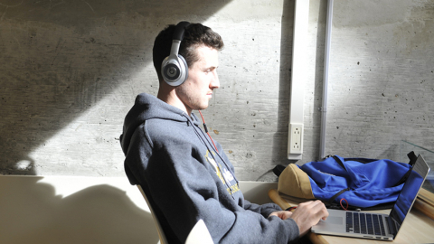 A UNBC student studies using a laptop and headphones